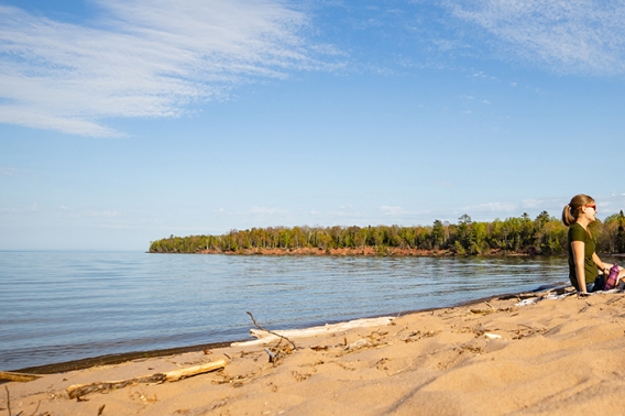 Couple sitting on the beach near a lake.